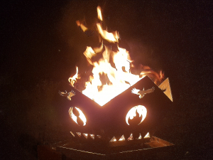 Lit pentagonal firepit with 5 elements symbols, at night
