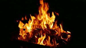A flaming fire pit warming people outdoors one evening