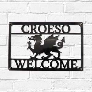 Arwydd Metel Du Draig Cymreig Dwyieithog 'Croeso Welcome' Welsh Dragon Bilingual Black Metal House Sign in Welsh & English on a white brick wall