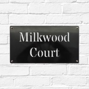 Classic rectangular metal house name plate sign in black steel on a white brick wall