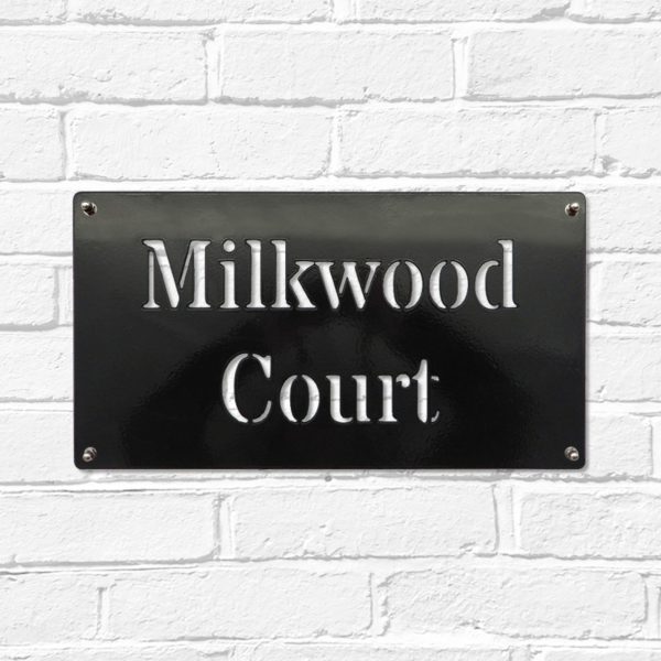 Classic rectangular metal house name plate sign in black steel on a white brick wall