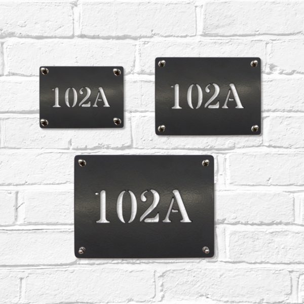 Small, medium and large classic rectangular metal house number signs in black steel on a white brick wall