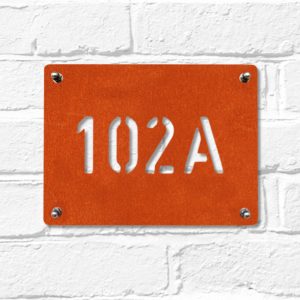 Modern rectangular metal house number in rusted industrial look Corten weathering steel on a white brick wall