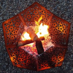 A lit black Star of Morocco Fire Pit BBQ and Ground Guard burning wood on a summer's evening