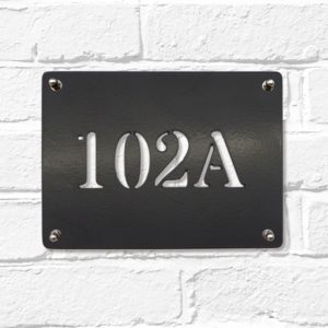 Classic rectangular metal house number sign in black steel on a white brick wall