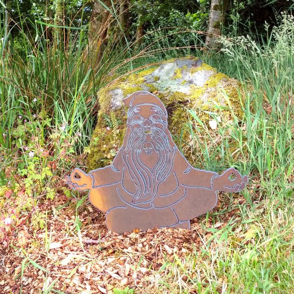 Rusty metal buddha gnome garden decor peacefully meditating in a beautiful woodland