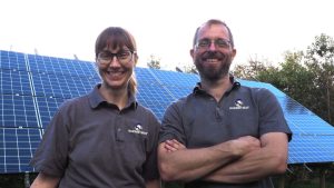 A smiling Jo and Nick of Ravens' Way with their solar photovoltaic panels