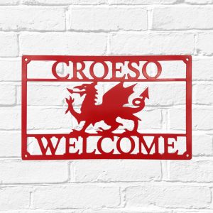 Arwydd Metel Coch Draig Cymreig Dwyieithog 'Croeso Welcome' Welsh Dragon Bilingual Red Metal House Sign in Welsh & English on a white brick wall
