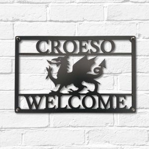 Arwydd Metel Du Draig Cymreig Dwyieithog 'Croeso Welcome' Welsh Dragon Bilingual House Sign in Fine Textured Black Metal in Welsh & English on a white brick wall