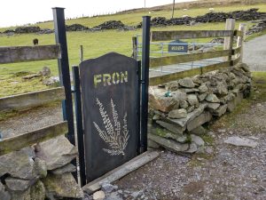 View of mountain-shaped CORTEN weathering steel gate with matching house name sign in the background