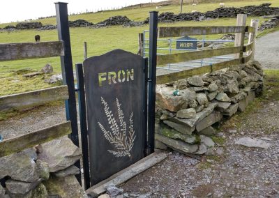 View of mountain-shaped CORTEN weathering steel gate with matching house name sign in the background