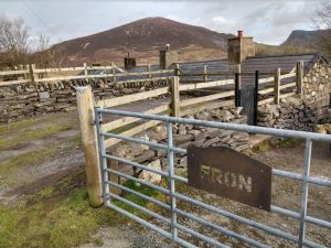 View of mountain-shaped CORTEN weathering steel house name sign, with gate and mountain in the background