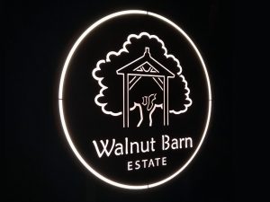 Closeup of backlit, stainless steel sign for Walnut Barn Estate at night
